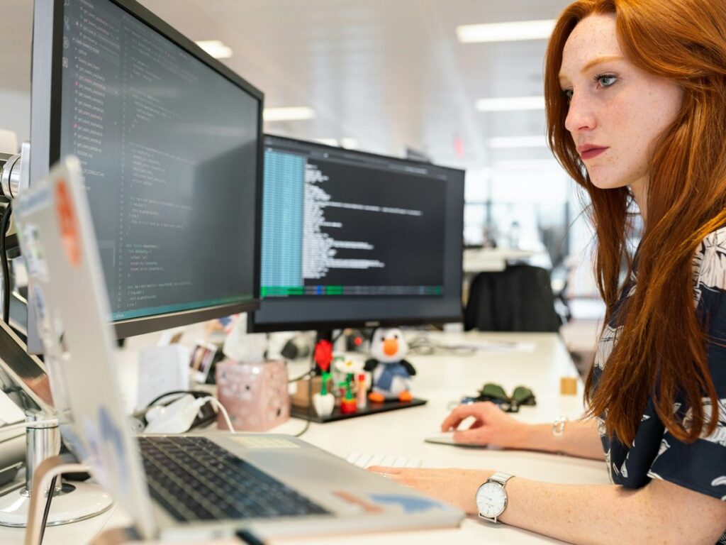 Developer writing code across two monitors